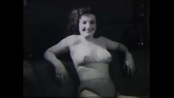 Odtwórz Dojrzała dama o ciemnych, jedwabistych włosach bierze udział w kręceniu filmu porno z lat 60